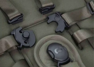 Close-up of an olive green tactical backpack with MOLLE straps and black quick-release buckles.